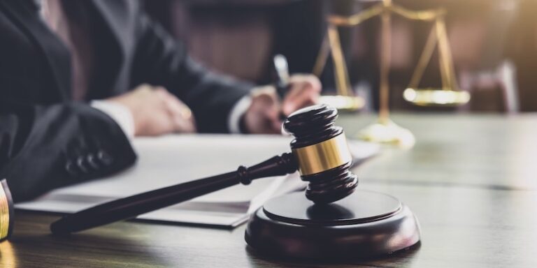 Judge gavel with Justice lawyers, Gavel on wooden table and Counselor or Male lawyer working on a documents at law firm in office. Legal law, advice and justice concept